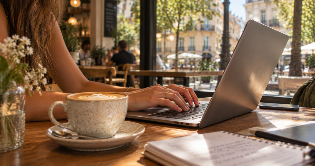 Manos de una joven trabajando con el portátil y un café
